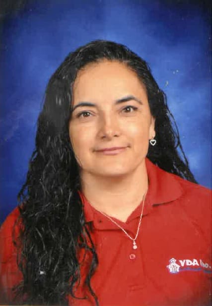 Portrait of a woman with long curly hair wearing a red polo shirt.